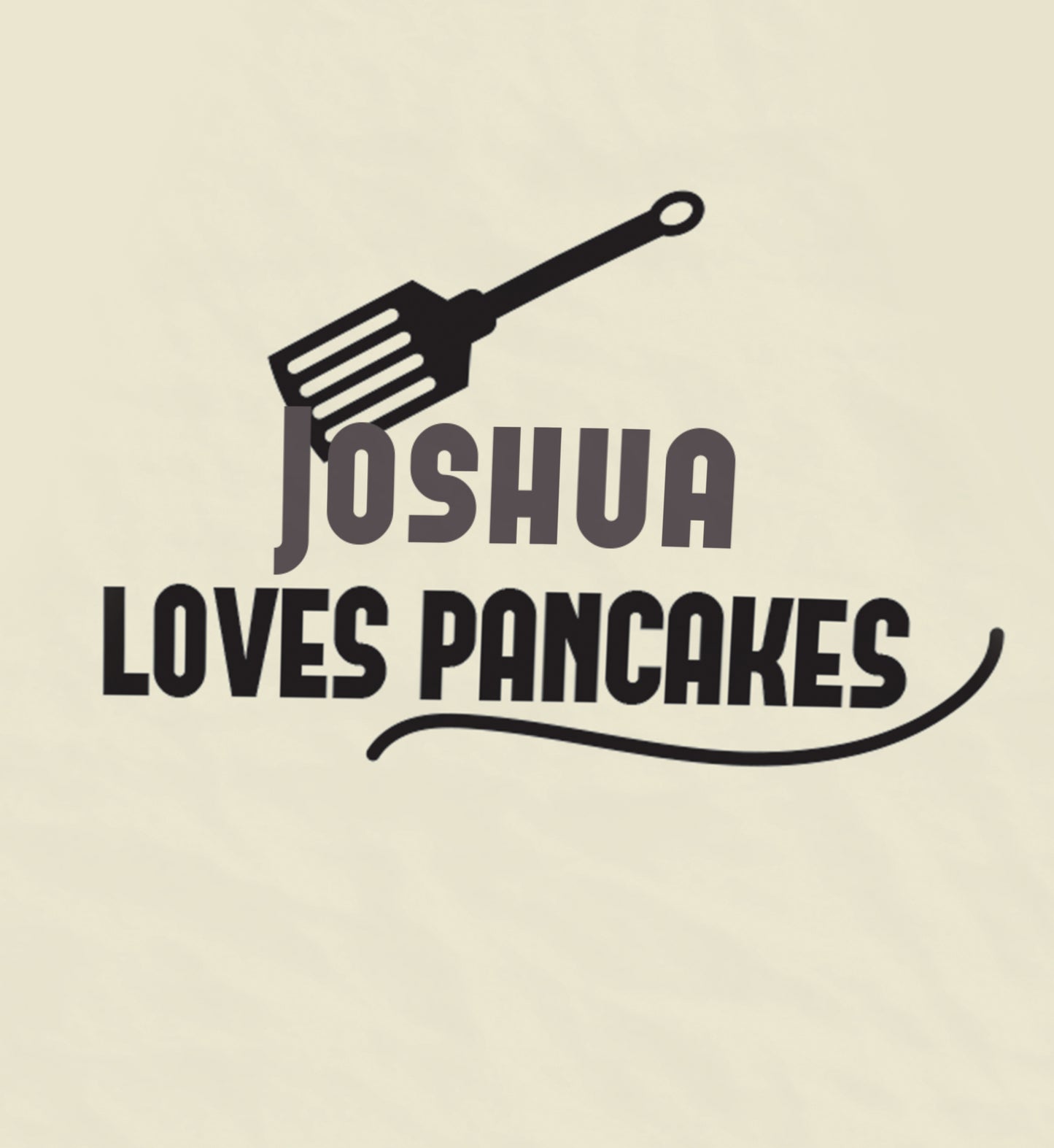 Close up of Personalised pancake day apron. Text on apon is Joshua loves pancakes. Spatula art.