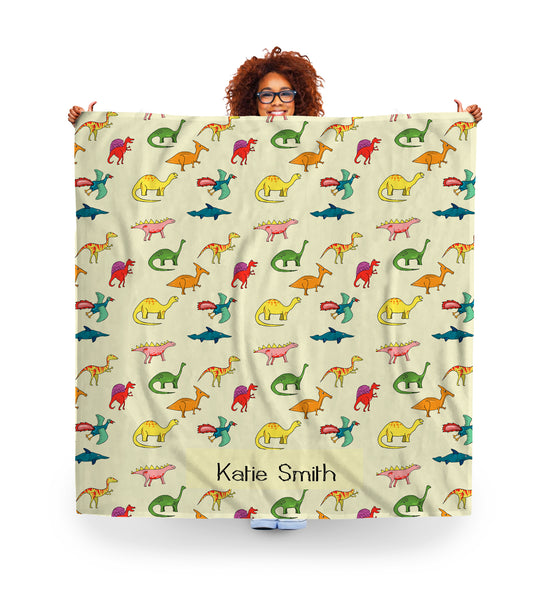 woman holding a personalised fleece blanket for kids. dinosaurs images and name