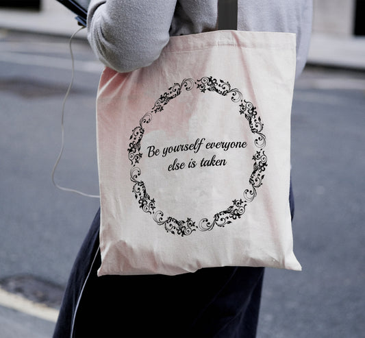 person wearing personalised tote bag with circle pattern and text in centre. black handles.