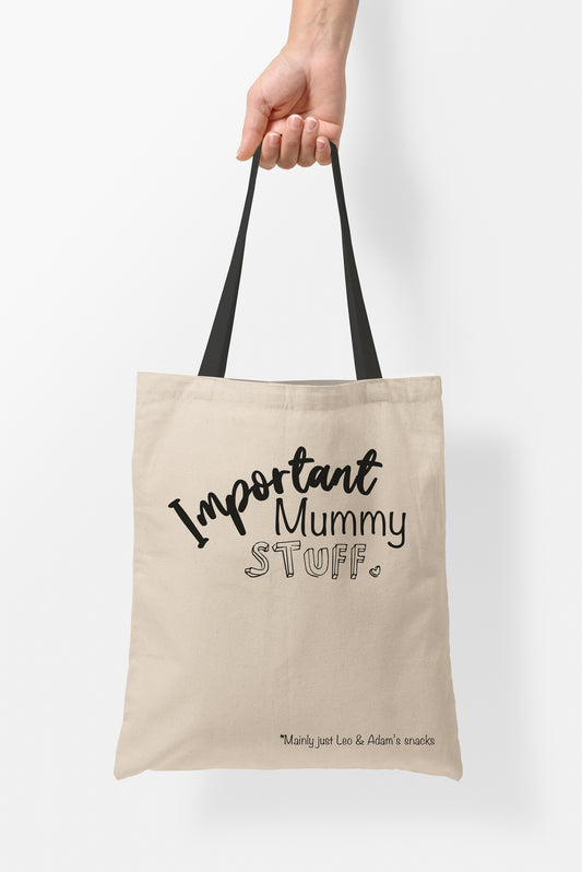 Mothers Day Tote Bags | Fab Gifts | Front View: Person holding Beige colour tote bag, Handle: Black, Text: Important Mommy Stuff. Mainly just Leo & Adam's snacks