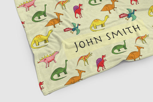 close up of a personalised fleece blanket for kids. dinosaurs images and name